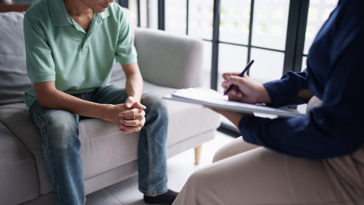 A client and therapist sit facing one another during a counseling session.