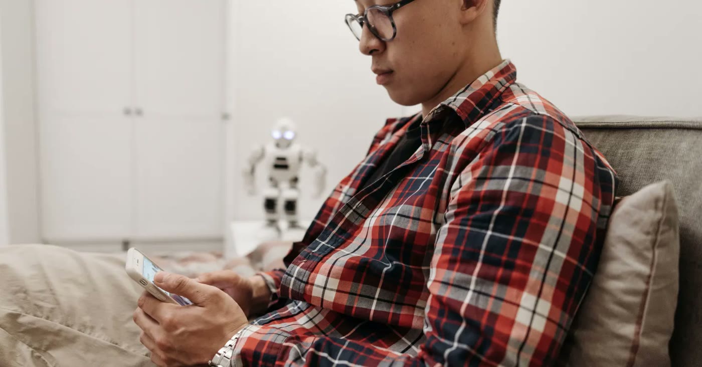 A person wearing glasses uses a smartphone while sitting at home.